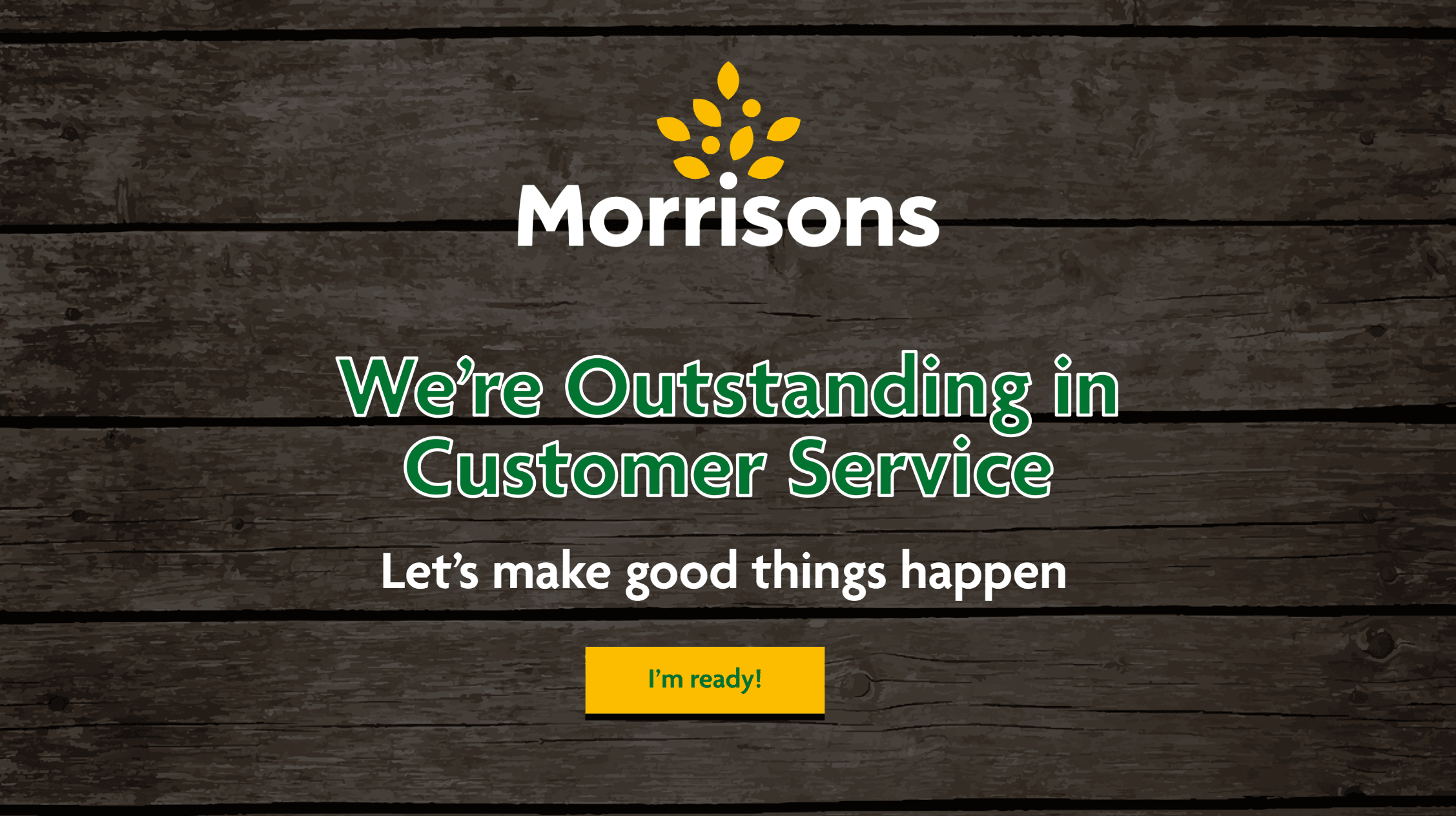 Title screen on a dark wooden background: the Morrisons logo above We're Outstanding in Customer Service, the line Let's make good things happen, and a yellow I'm ready! button.